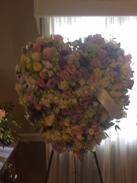 Large heart-shaped floral spray on a stand with pastel roses and mixed blooms