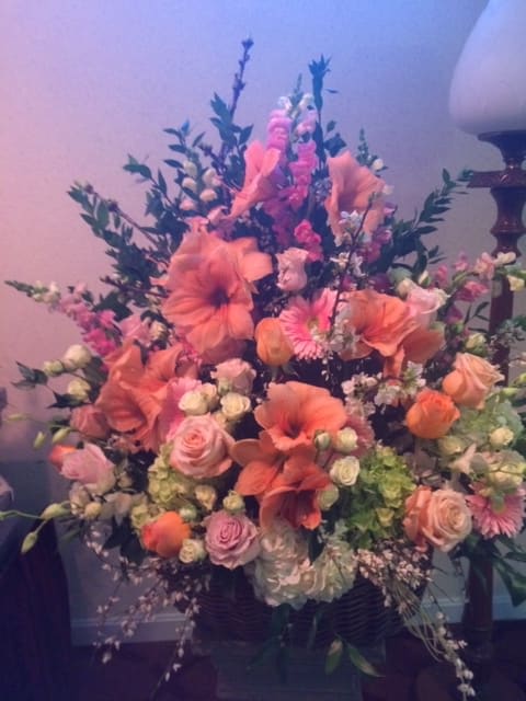 Large pink and peach floral arrangement in a dark vase