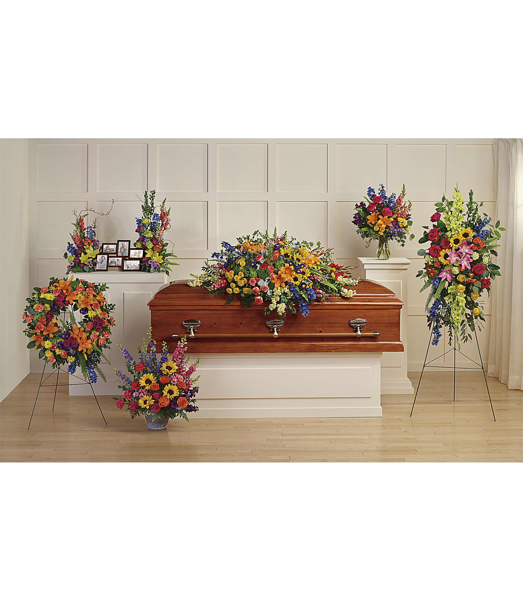 Colorful funeral casket spray with standing floral arrangements