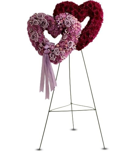 Two heart-shaped floral stands with pink and burgundy flowers on metal easels