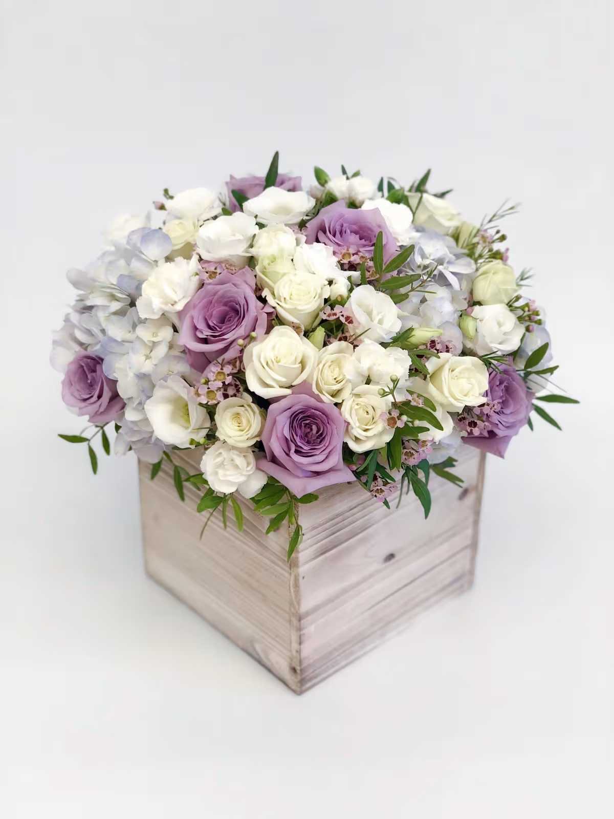 Lavender and white roses arranged in a wooden box