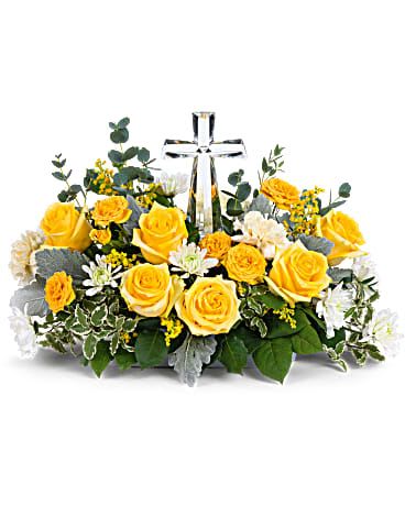 Yellow roses and white flowers arranged around a clear cross