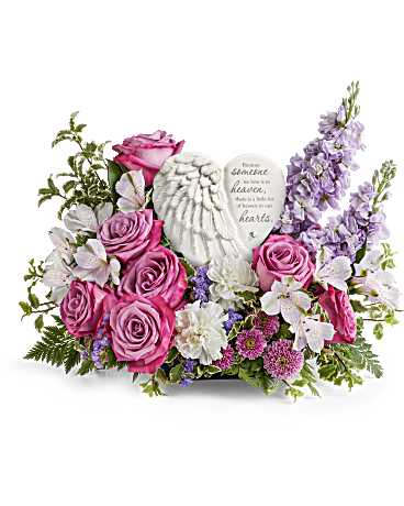 Pink roses and white flowers arranged around a memorial heart plaque
