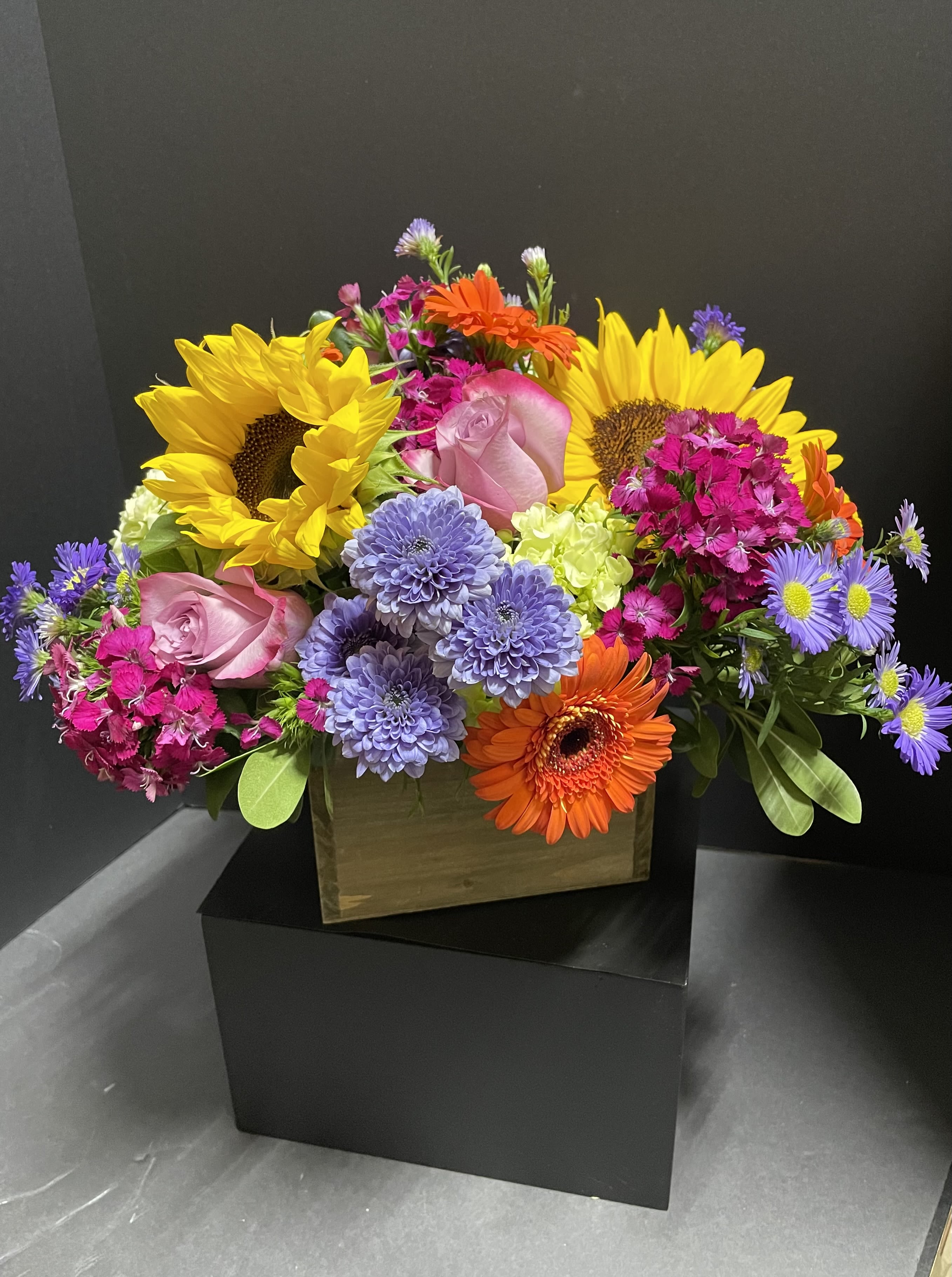 Colorful mixed bouquet with sunflowers, roses, and gerbera daisies in a box
