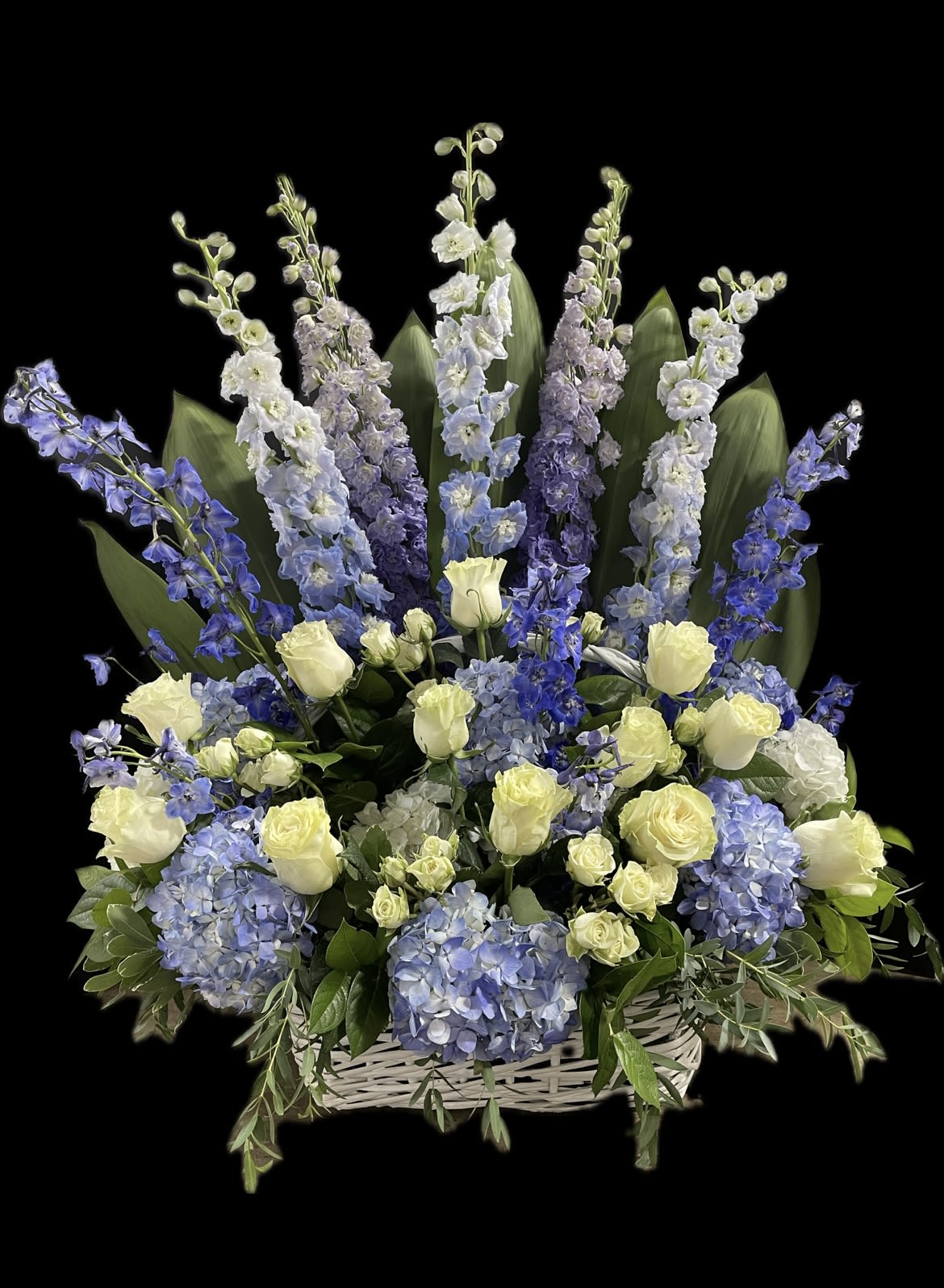 Blue and white floral arrangement in a white basket