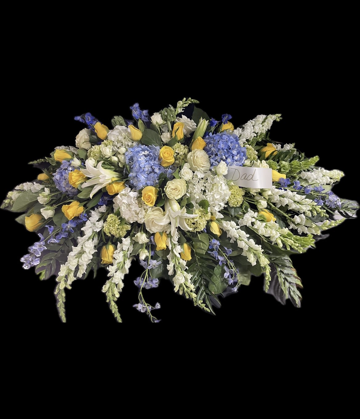 Large floral spray with yellow roses, white lilies, and blue hydrangeas