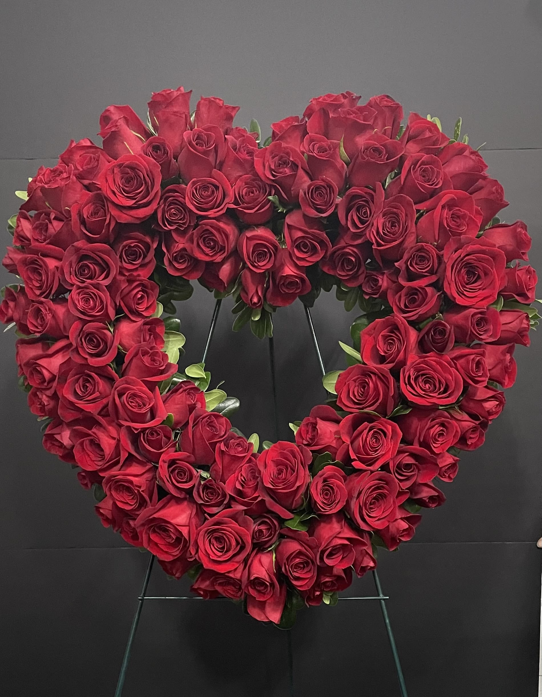 Heart-shaped wreath of red roses on a stand