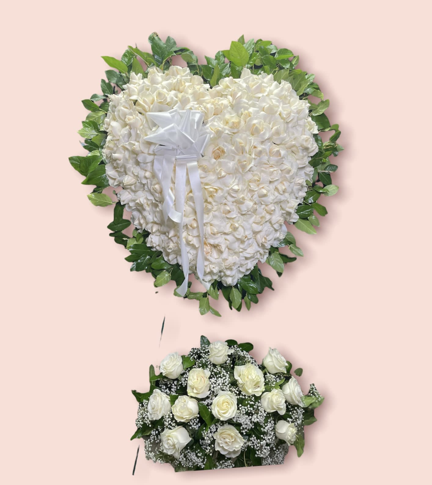 White heart-shaped floral tribute with a white ribbon and green border