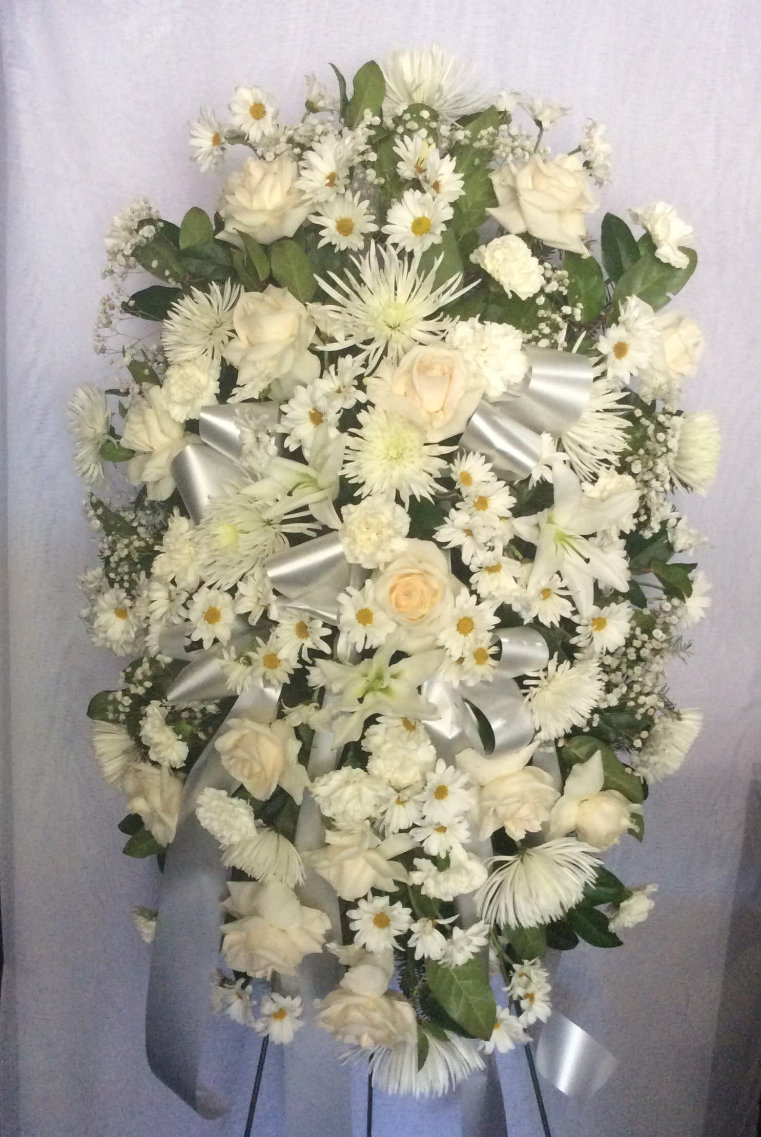 White floral standing spray with roses, daisies, and lilies