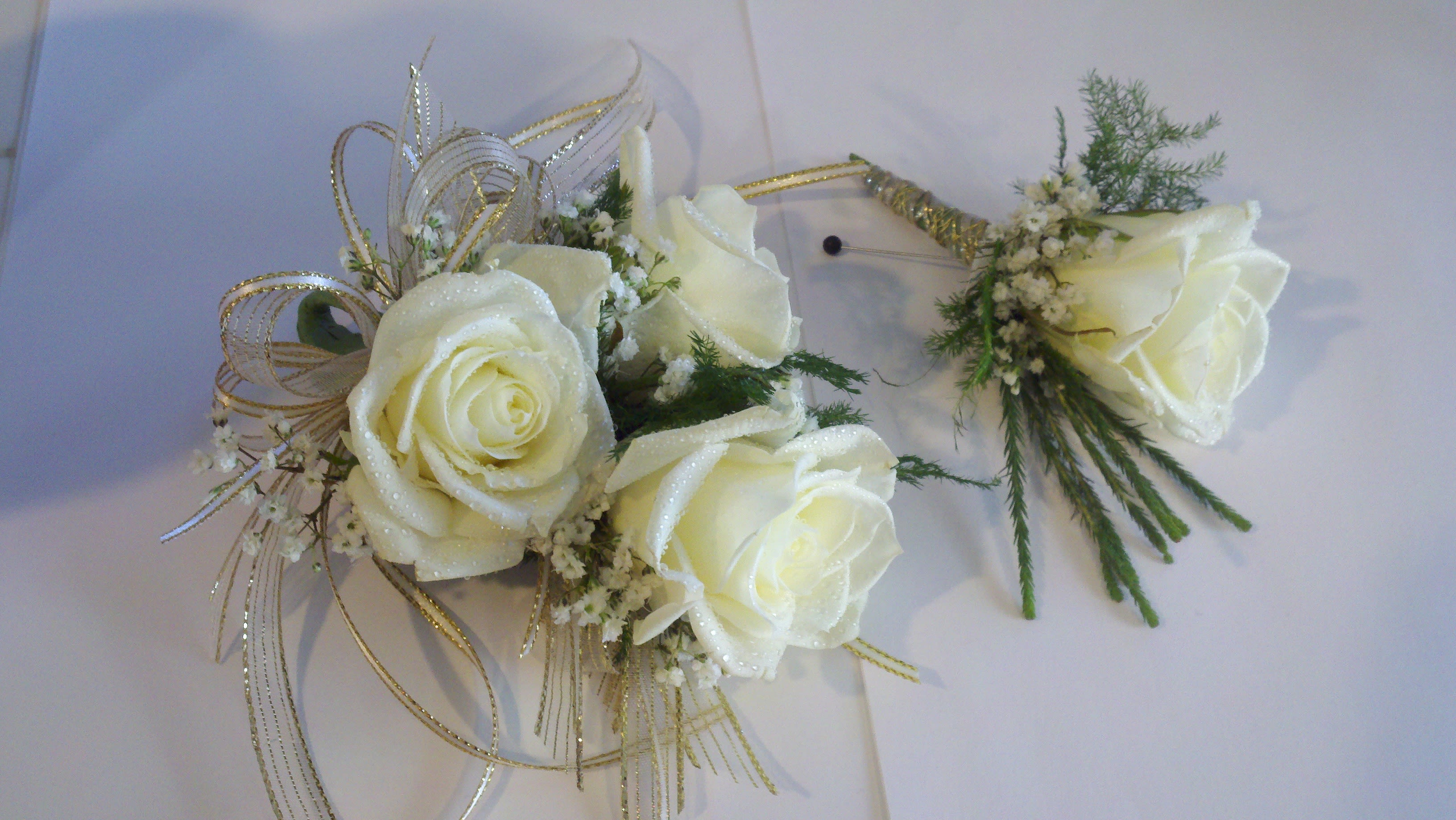 White rose corsage and boutonniere with gold ribbon accents