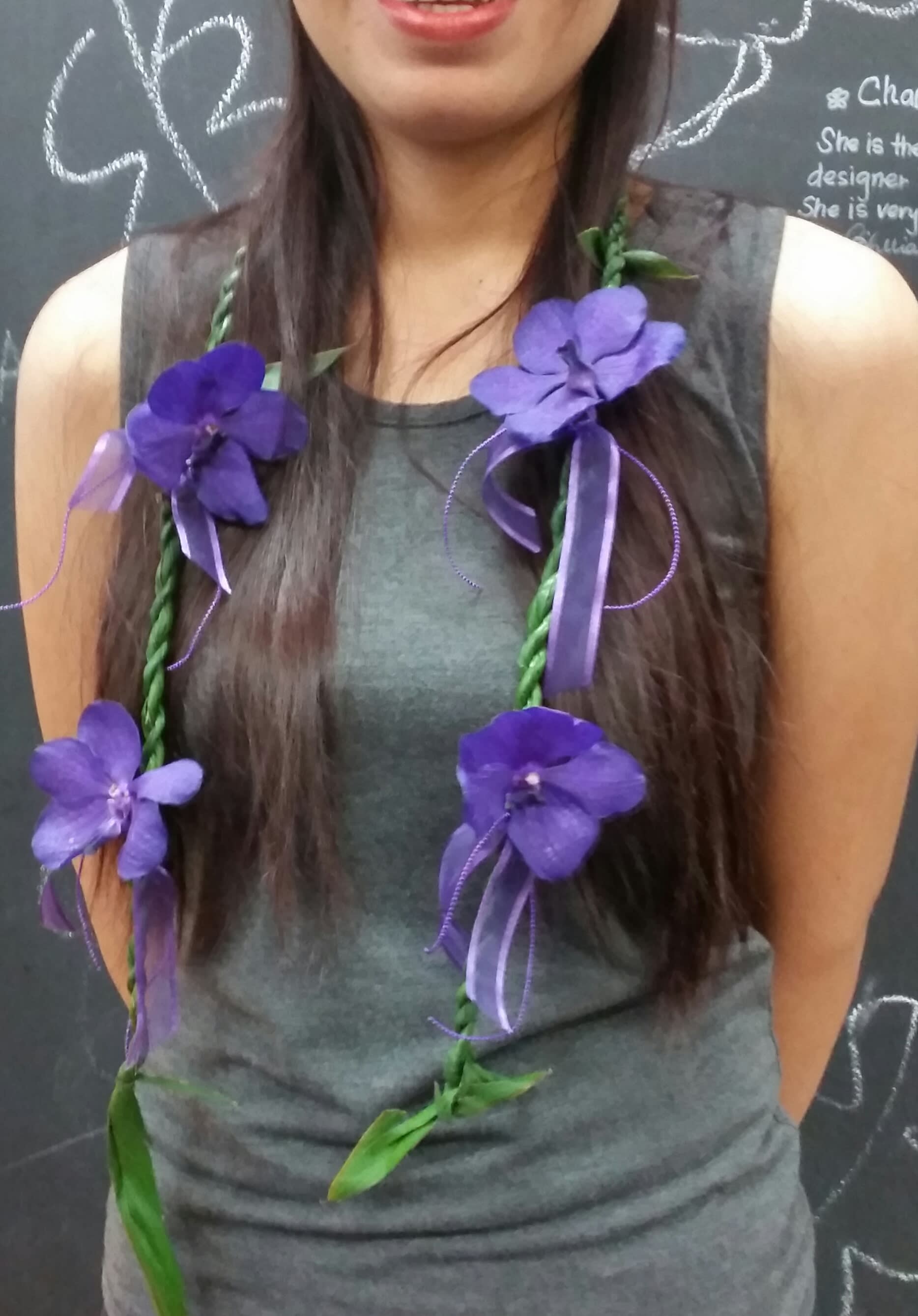 Woman wearing a purple flower lei with ribbon accents