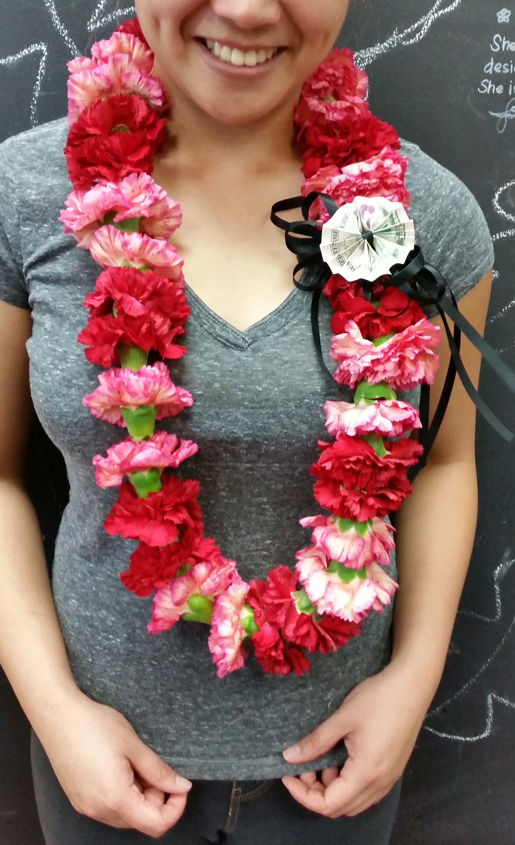 Woman wearing a lei of red and pink carnations with a black ribbon bow