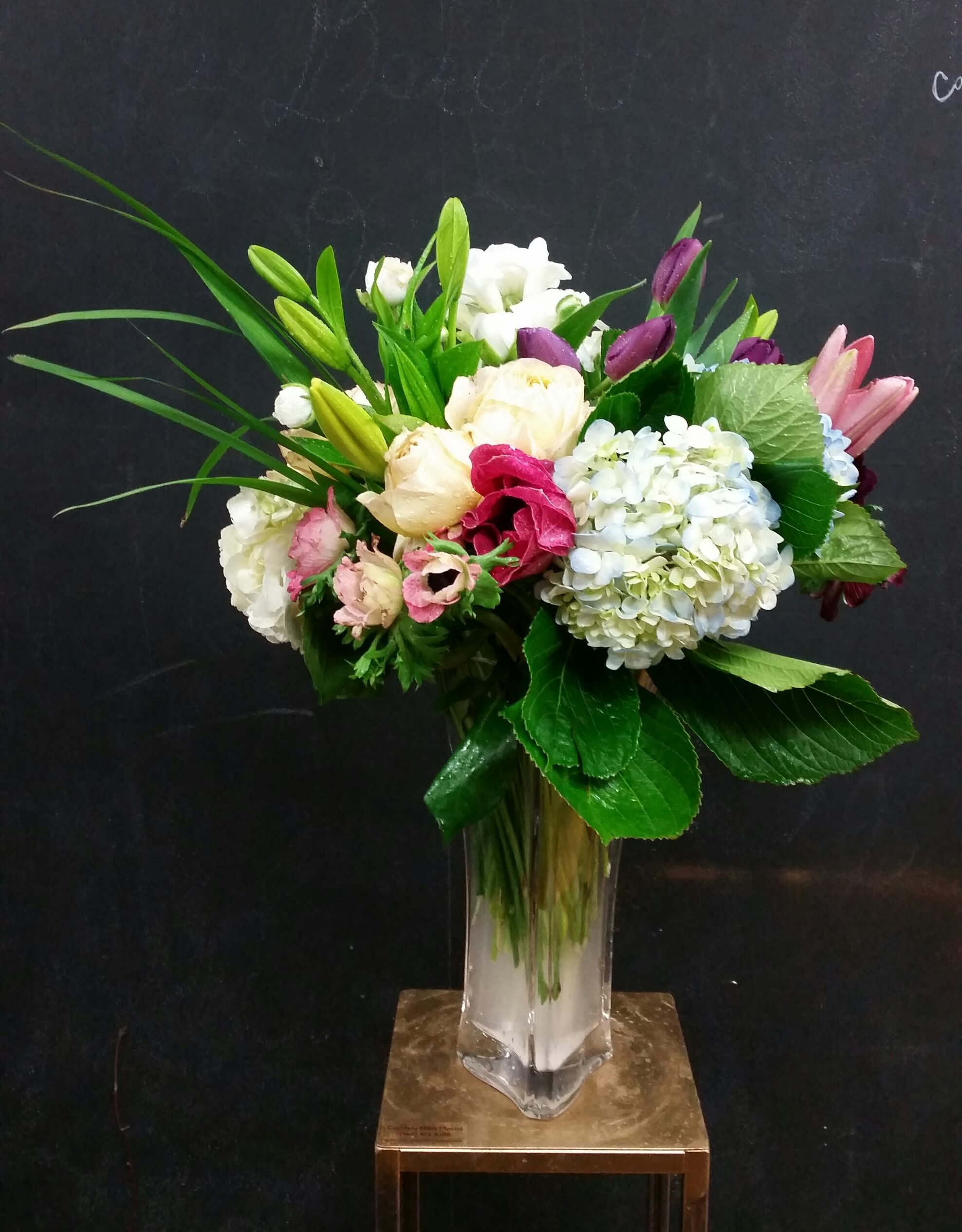 Mixed bouquet of white, pink, and purple flowers in a clear glass vase