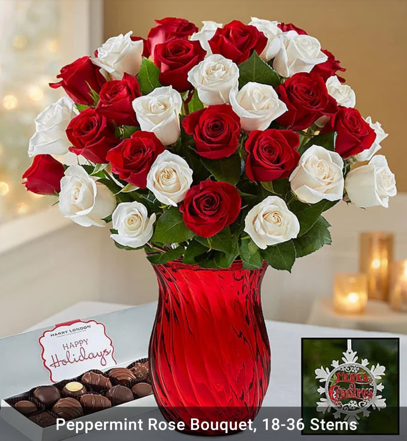 Red and white roses in a red glass vase with chocolates and a holiday card