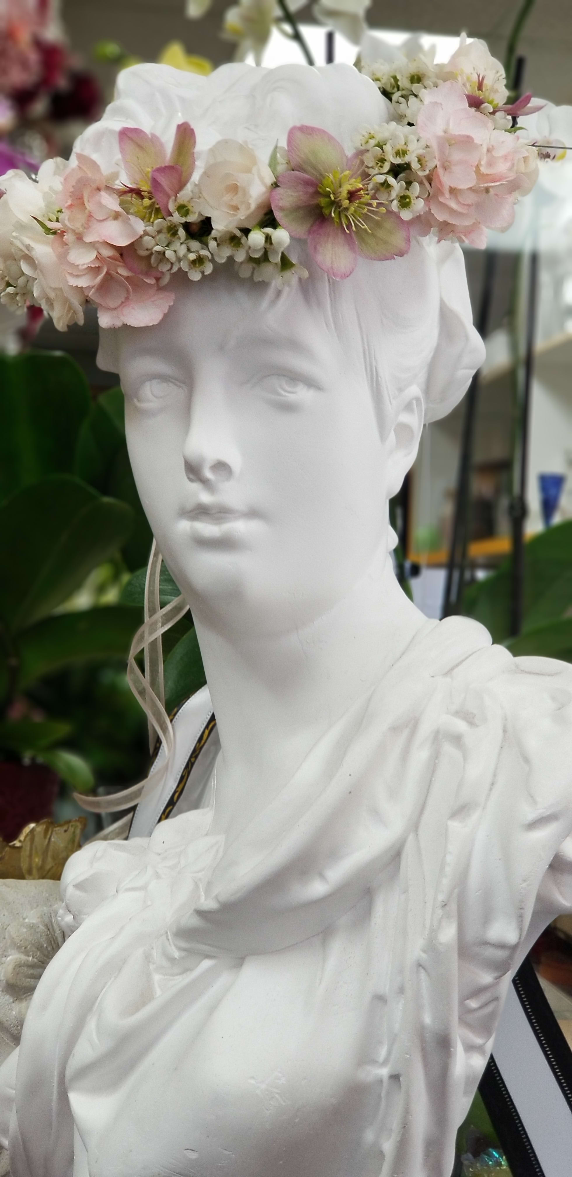 White bust wearing a pastel flower crown with pink and white blooms