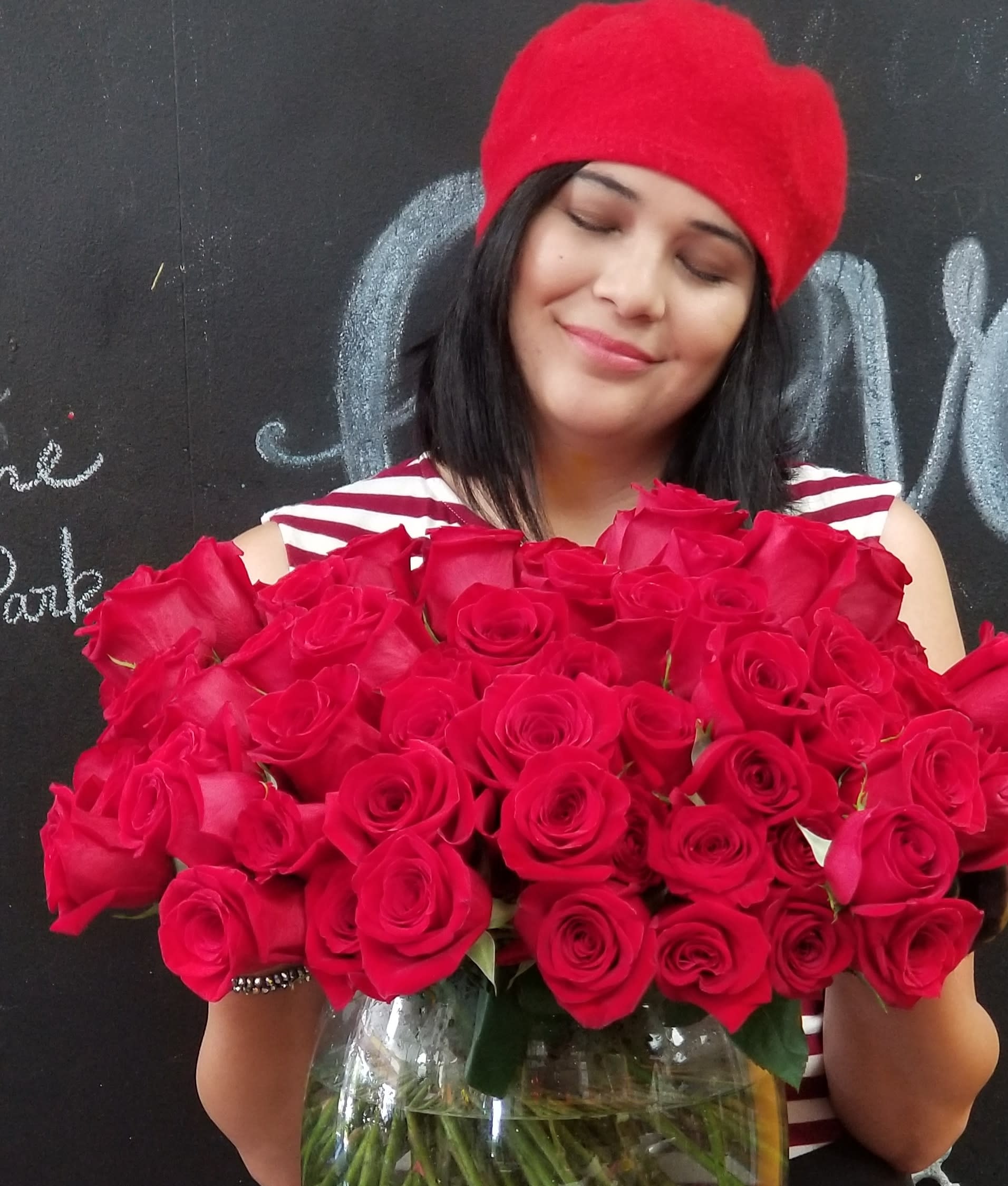 Woman holding a large bouquet of red roses in a glass vase