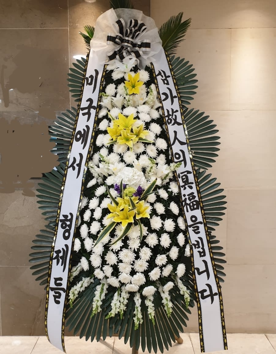 Standing funeral wreath with white and yellow flowers and Korean condolence ribbons