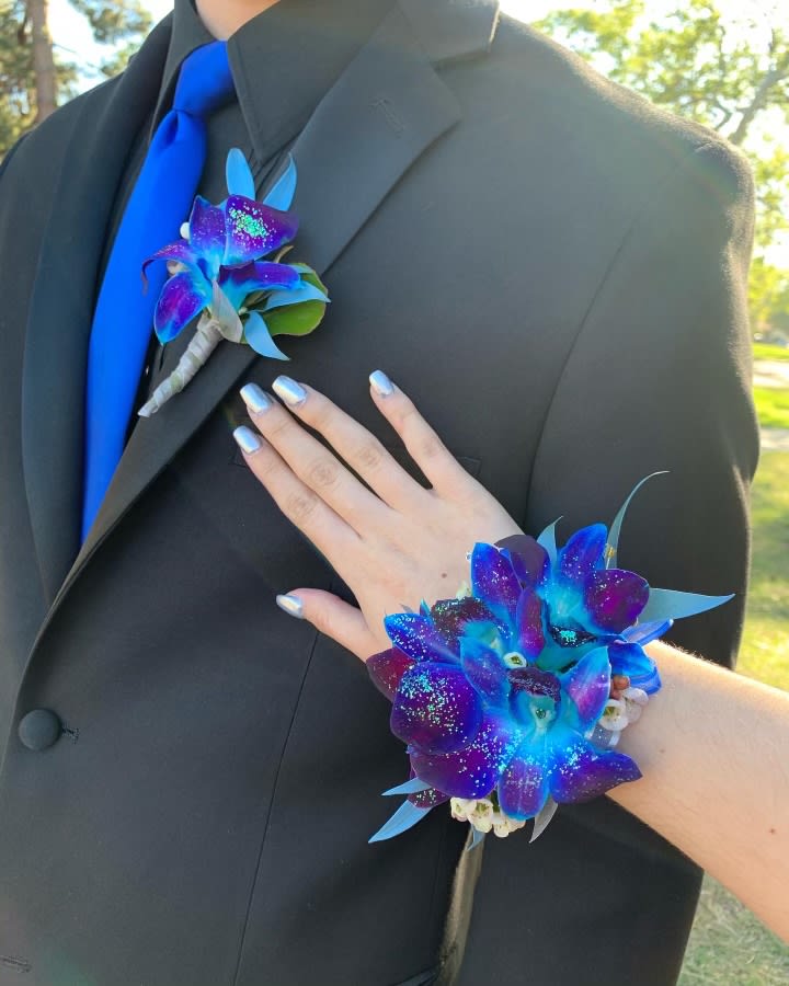 Blue and purple orchid boutonniere and matching wrist corsage on a black suit