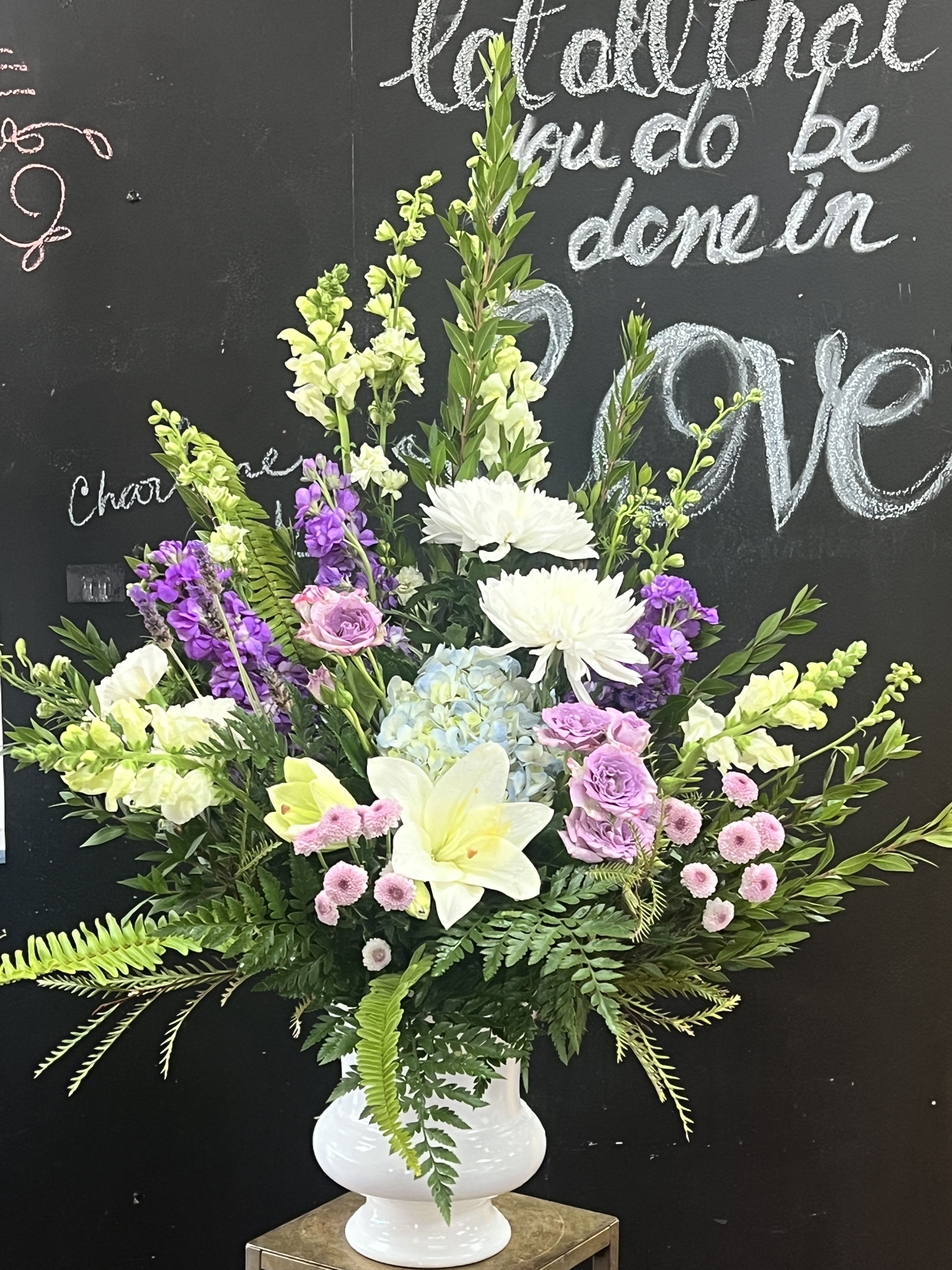 Large mixed floral arrangement in a white pedestal vase