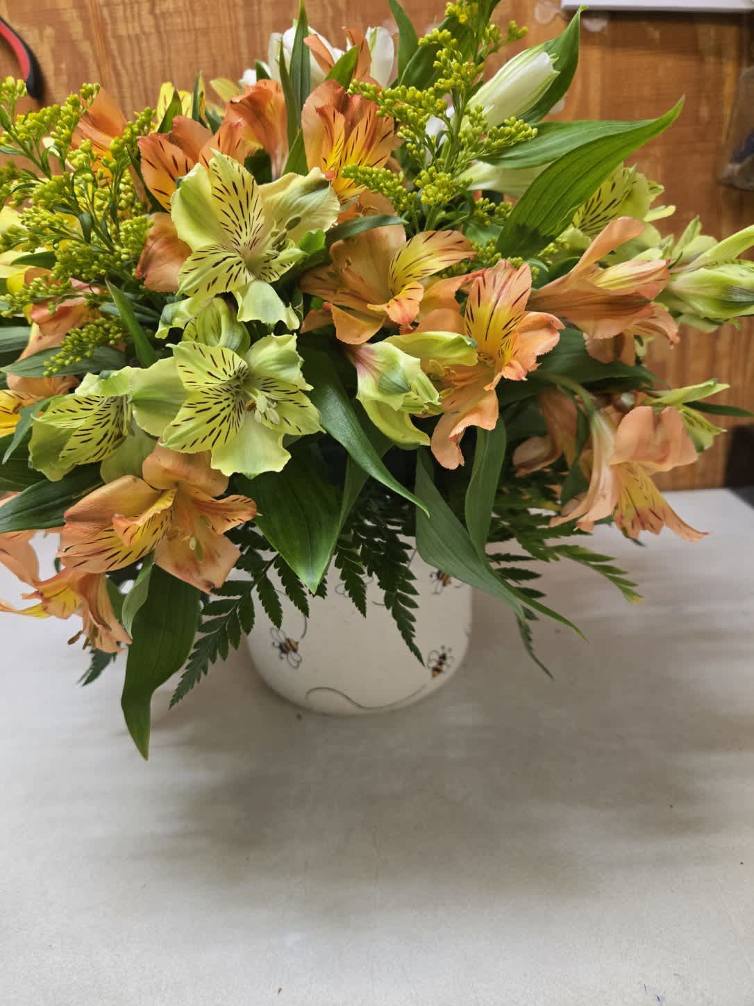 Orange and pale green alstroemeria in a white ceramic vase