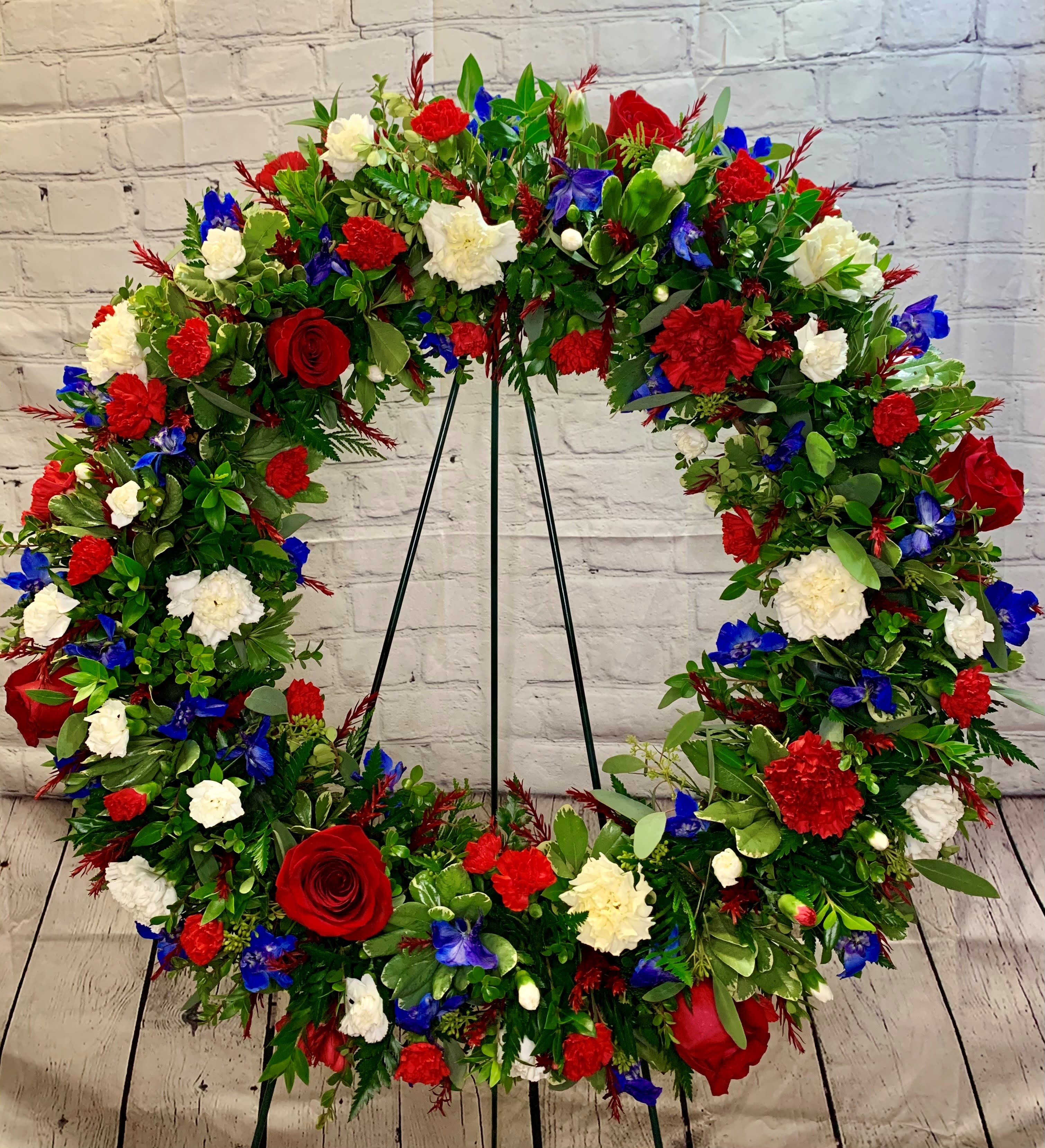 Large floral wreath with red, white, and blue flowers on a stand