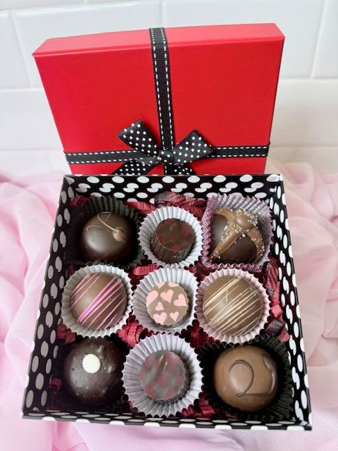 Box of assorted chocolates with a red lid and black ribbon