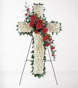 Standing floral cross with white flowers and red roses on an easel