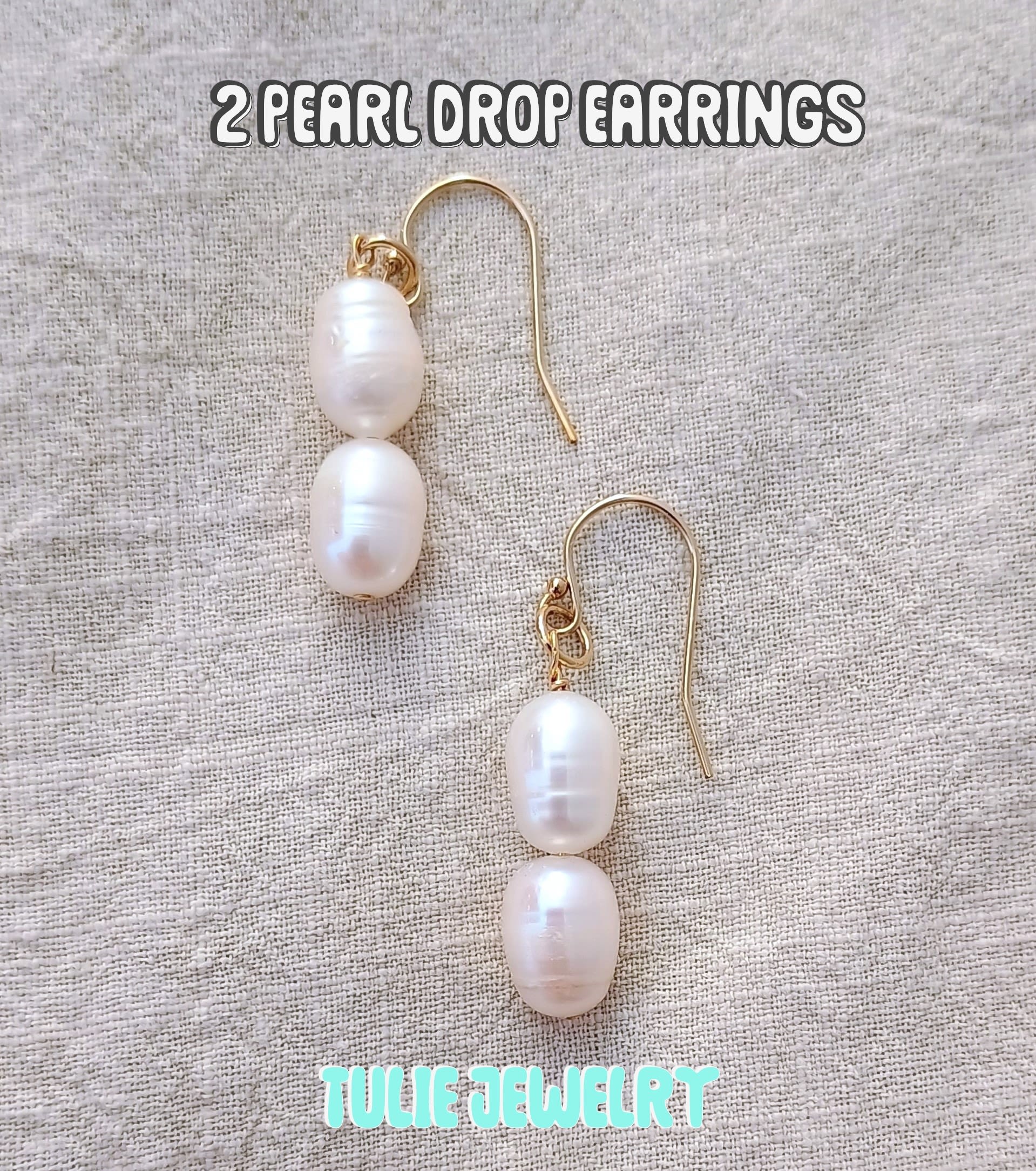Pair of pearl drop earrings with gold hooks on a fabric background
