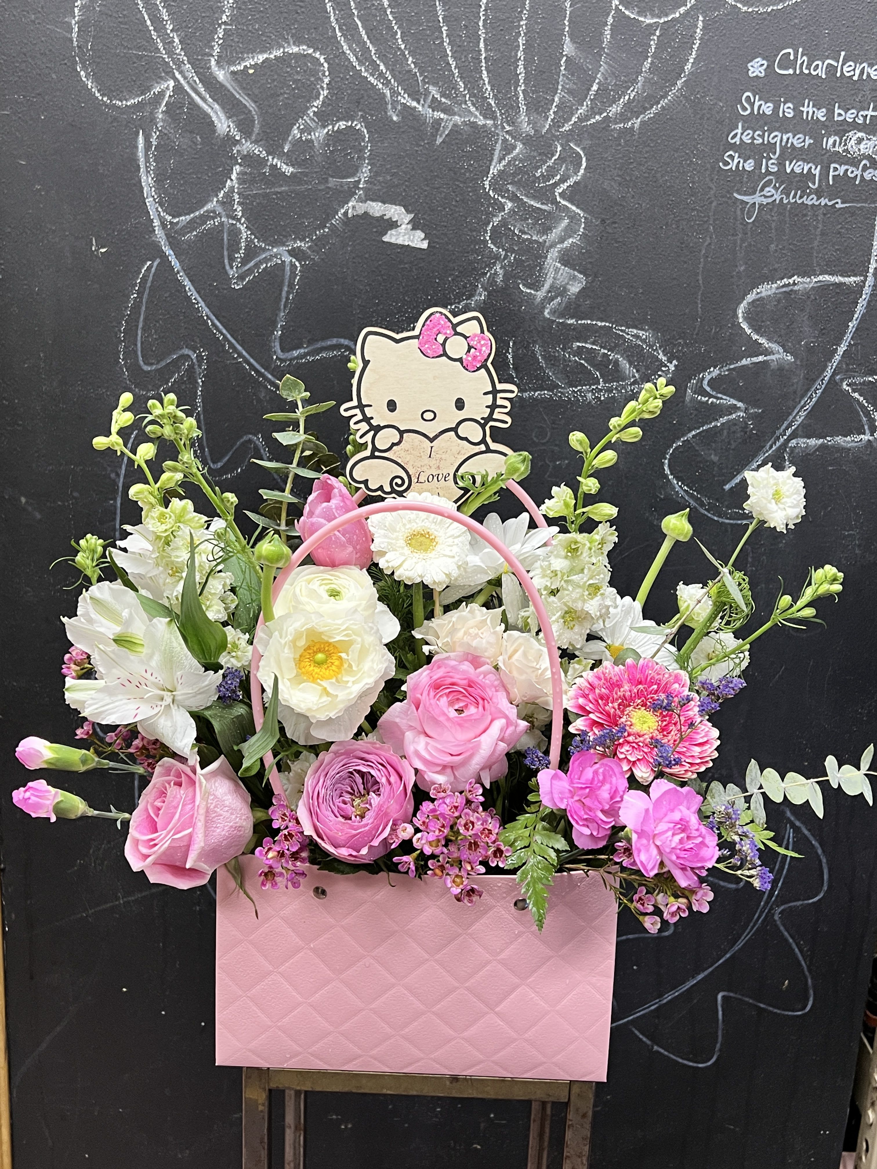 Pink and white flower arrangement in a pink gift bag with a Hello Kitty topper