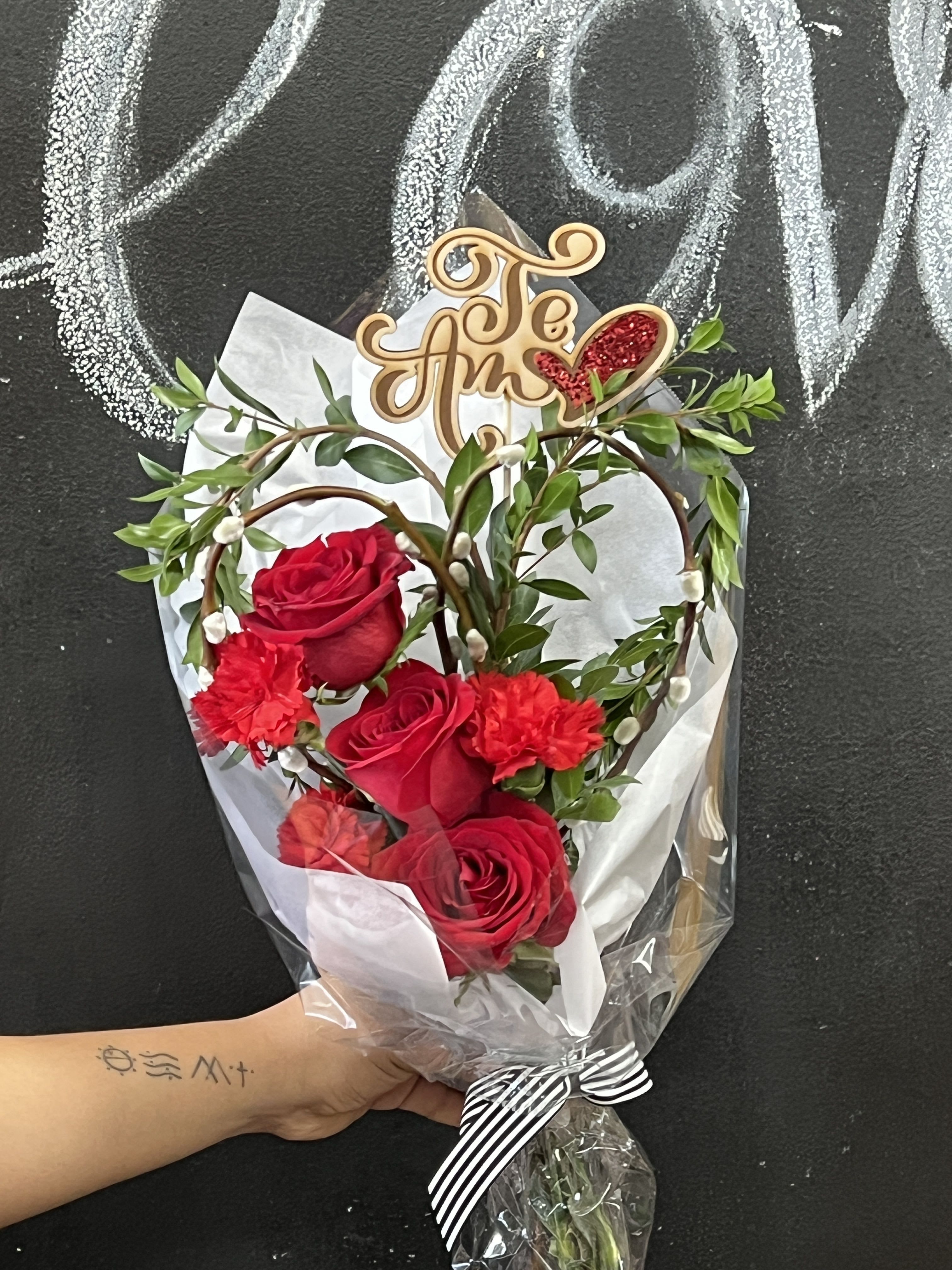 Bouquet of red roses and carnations with a decorative topper