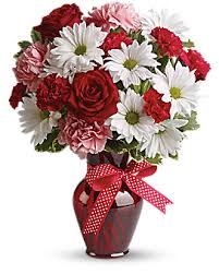 Red and white bouquet in a vase with a red ribbon