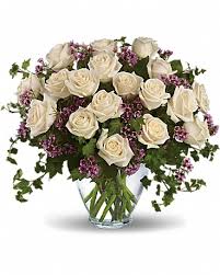 White roses and purple filler flowers in a clear glass vase
