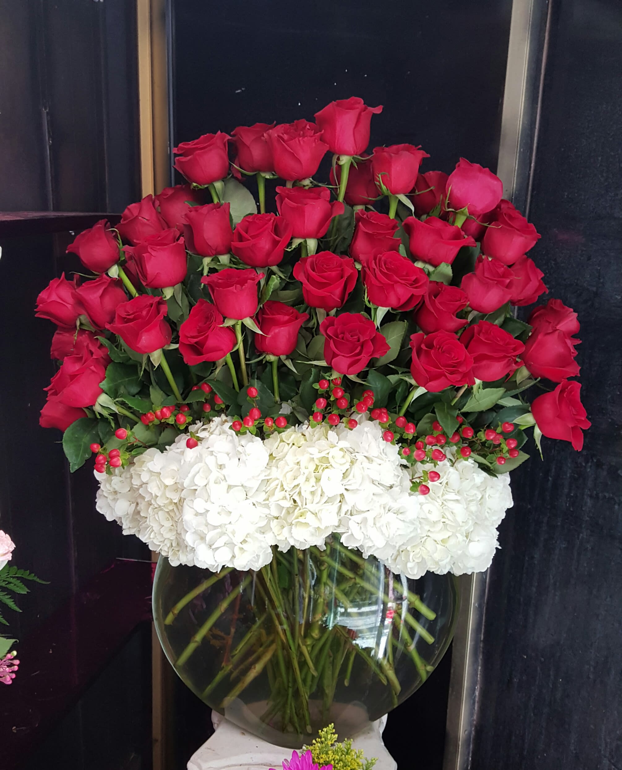 Red roses and white hydrangeas arranged in a glass vase