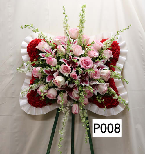 Standing floral spray with pink roses and red carnations on a white easel