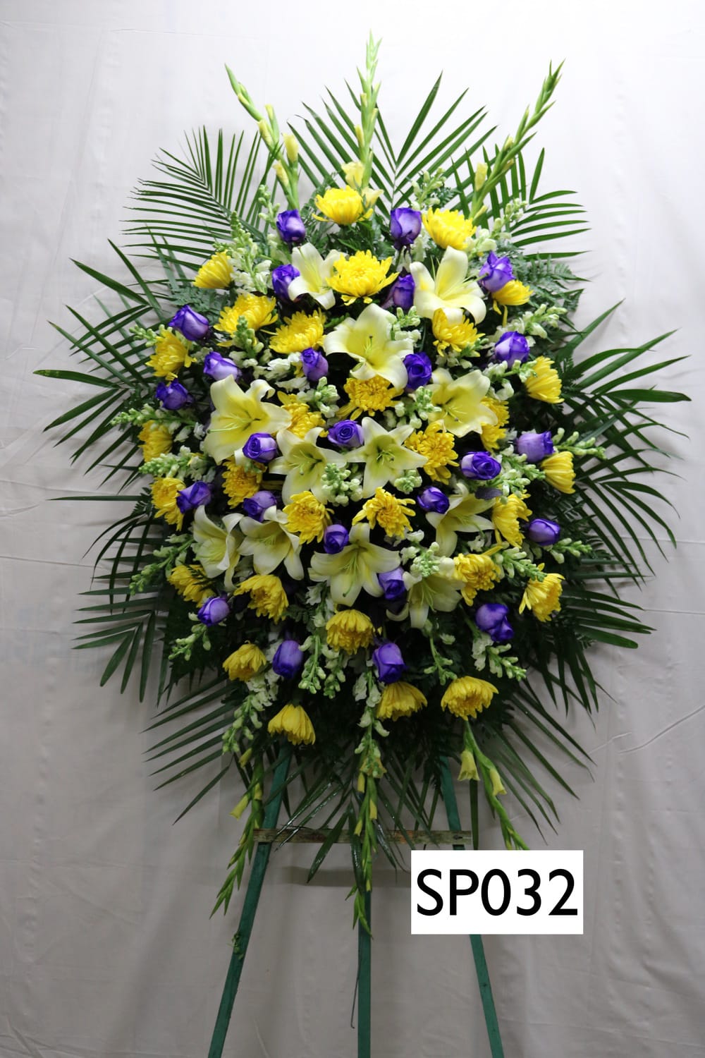Standing floral spray with yellow and purple flowers on a frame
