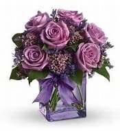 Purple rose bouquet in a square glass vase with a ribbon