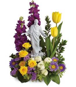 Floral arrangement with a white statue centerpiece, yellow tulips, and purple flowers