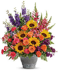 Mixed bouquet with sunflowers, orange roses, and purple flowers in a gray vase