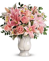 Pink roses and lilies arranged in a white vase