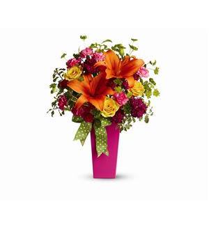 Bouquet of orange lilies and mixed flowers in a pink vase with ribbon