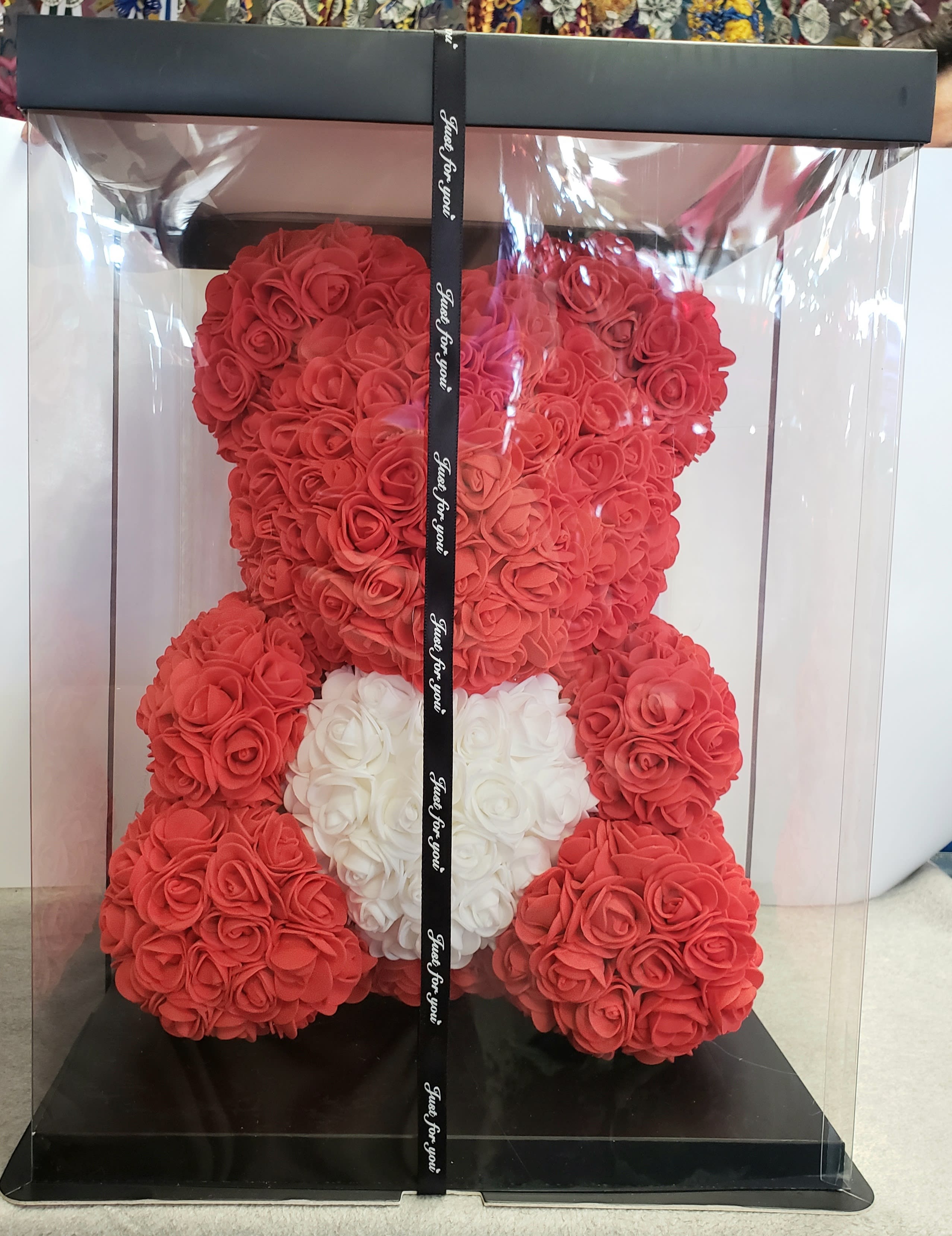 Red teddy bear made of roses in a clear gift box with a white heart