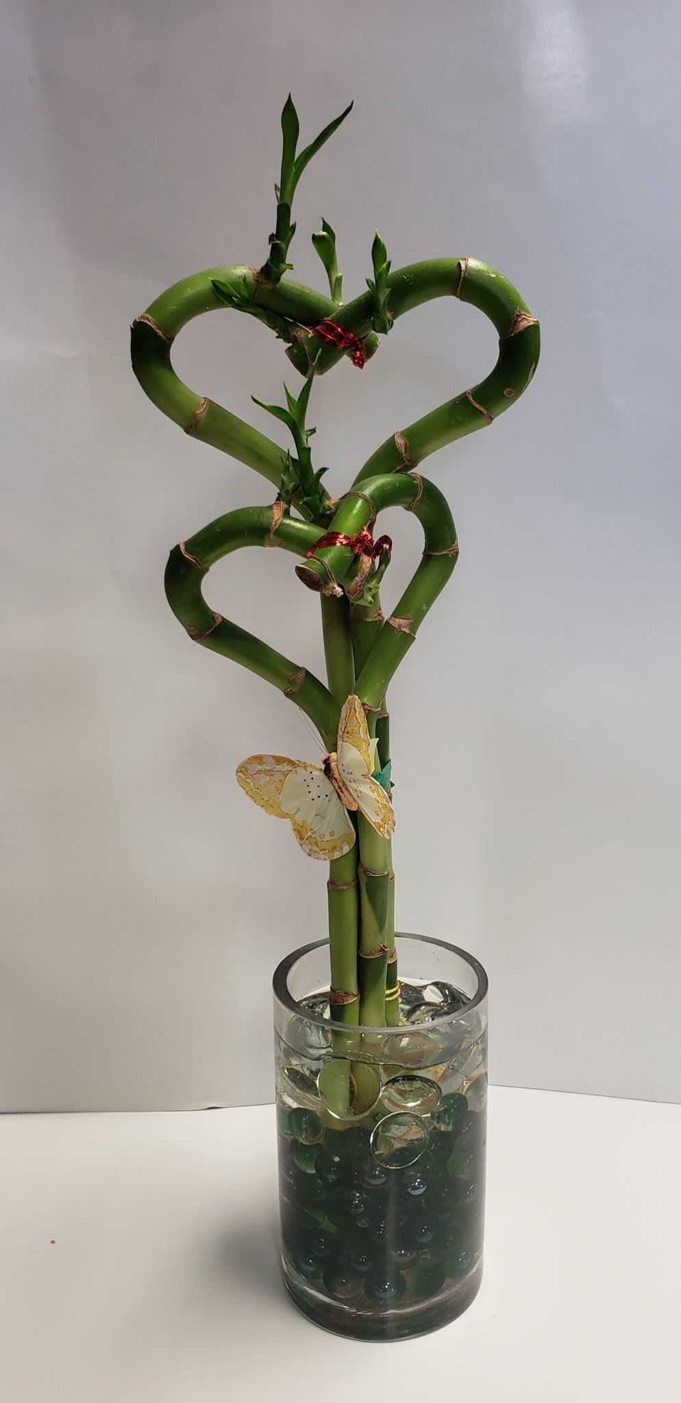 Heart-shaped lucky bamboo in a glass vase with decorative stones