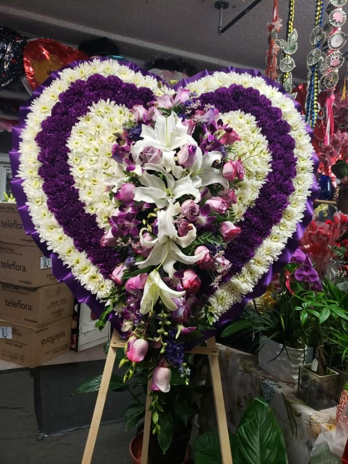 Heart-shaped floral standing spray with white, purple, and pink flowers