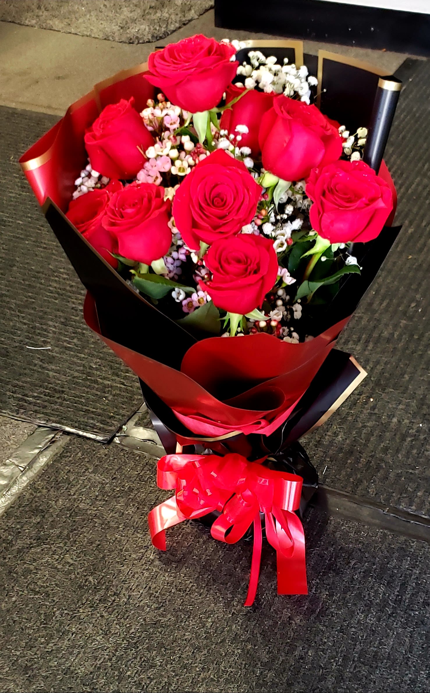 Bouquet of red roses with baby's breath wrapped in red and black paper
