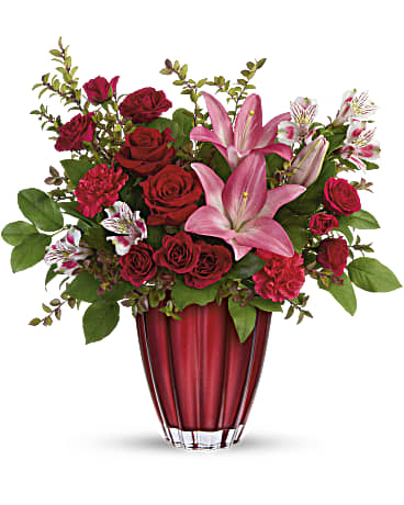 Red roses and pink lilies in a red glass vase
