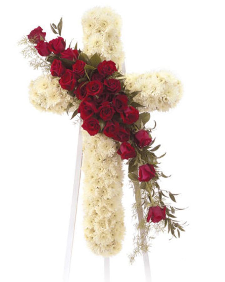 Red roses arranged on a white floral cross