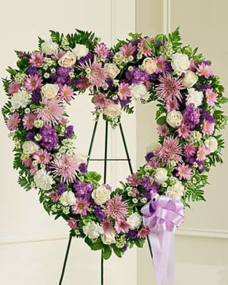 Heart-shaped floral wreath with pink, purple, and white flowers on an easel