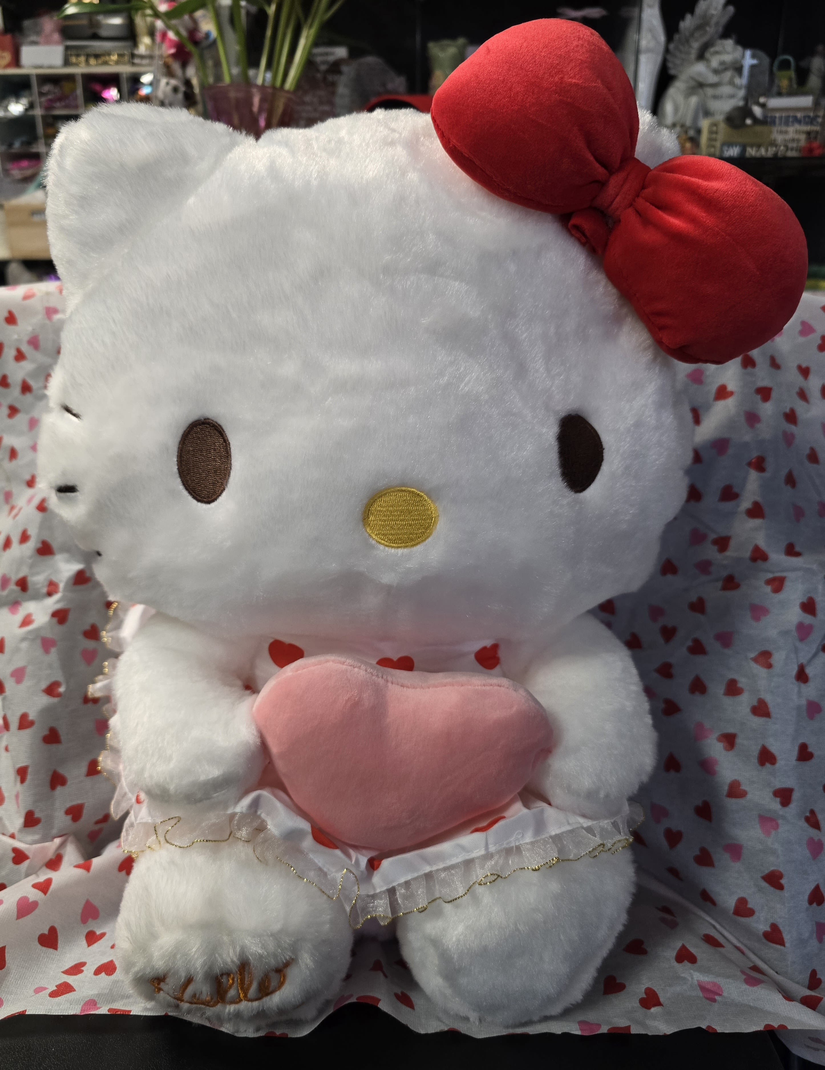 Hello Kitty plush holding a pink heart pillow