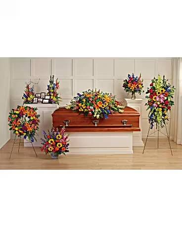 Colorful funeral casket spray with standing floral tributes