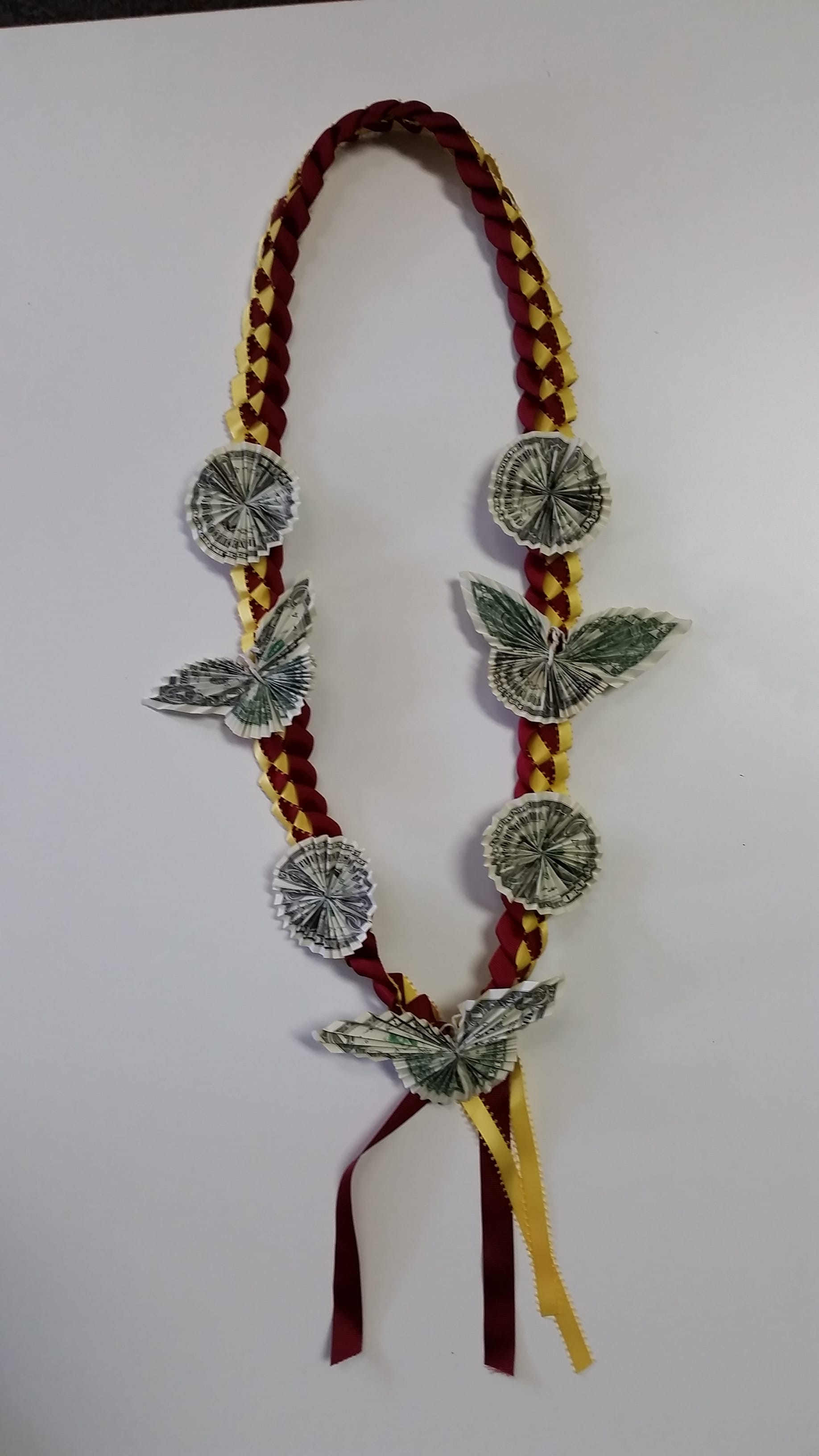 Braided ribbon garland decorated with folded dollar bills and butterfly shapes